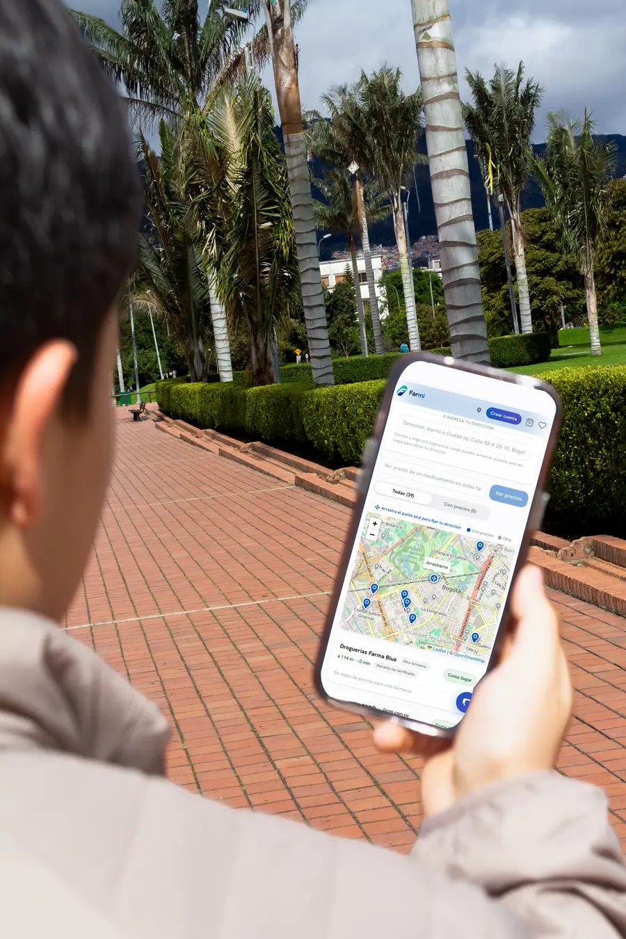 Persona usando Farmi en la calle para encontrar farmacias cercanas en el mapa